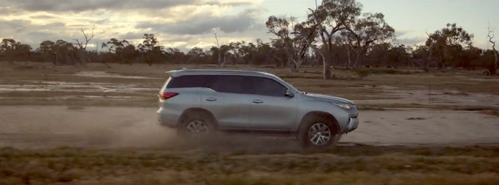 a silver suv driving on a dirt road