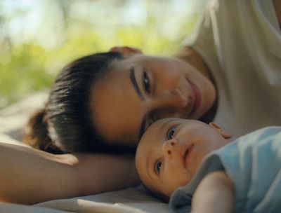 a woman and a baby laying on a bed