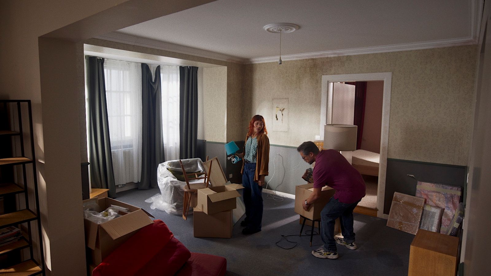 a man and a woman unpack boxes in a living room