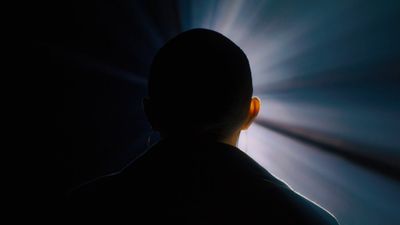 a silhouette of a man in a dark room with a light coming from behind him