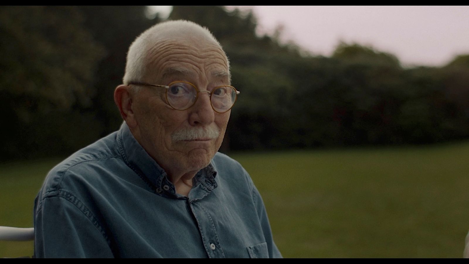 an old man with glasses sitting in a chair