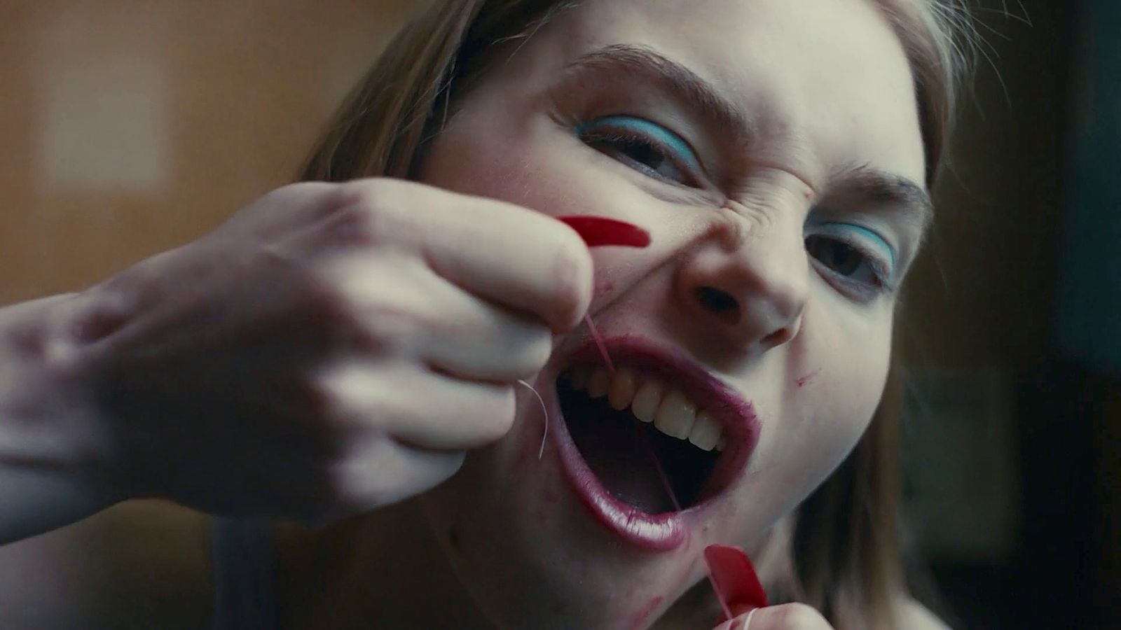 a girl with blue and red makeup is brushing her teeth