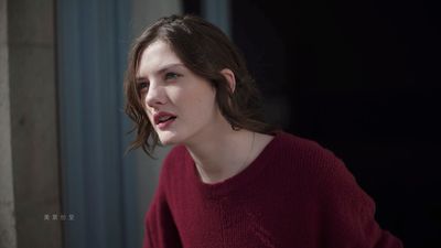 a woman in a red sweater looking off into the distance