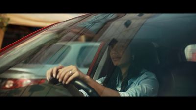 a woman sitting in a car with her hand on the steering wheel