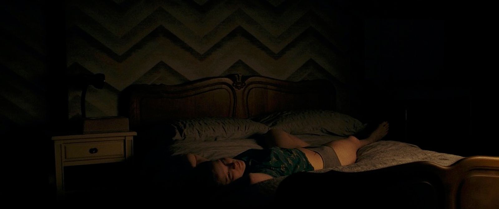 a woman laying on a bed in a dark room