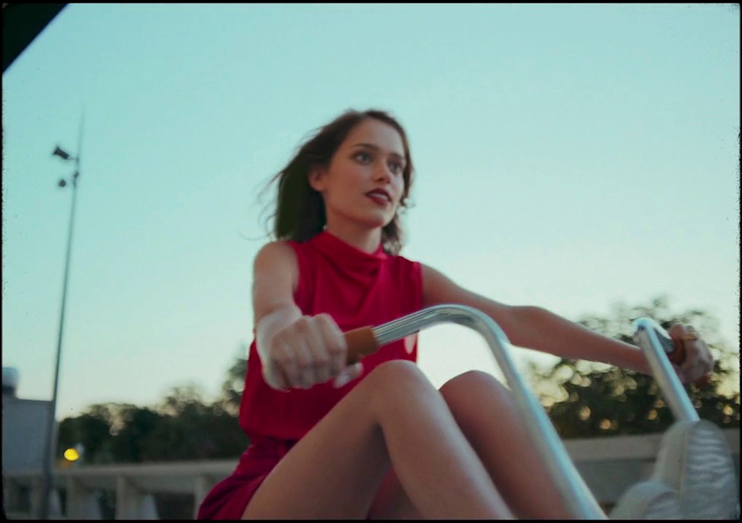 a woman in a red dress riding a scooter