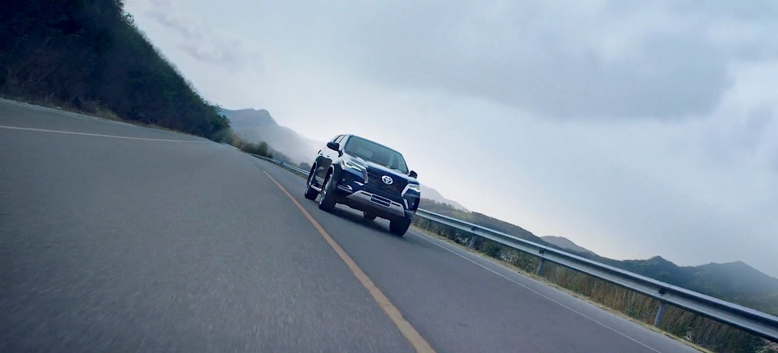 a car driving down a road with mountains in the background