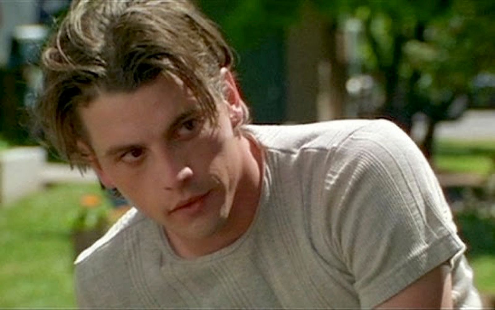 a young man sitting on a bench in a park