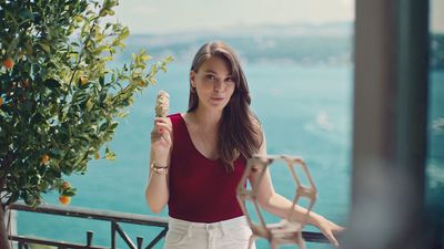 a woman holding an ice cream cone standing next to a tree