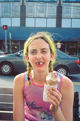 a woman sitting on a bench eating an ice cream cone