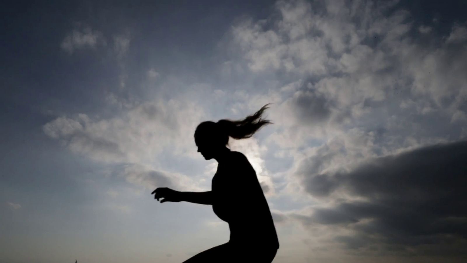 a silhouette of a woman throwing a frisbee