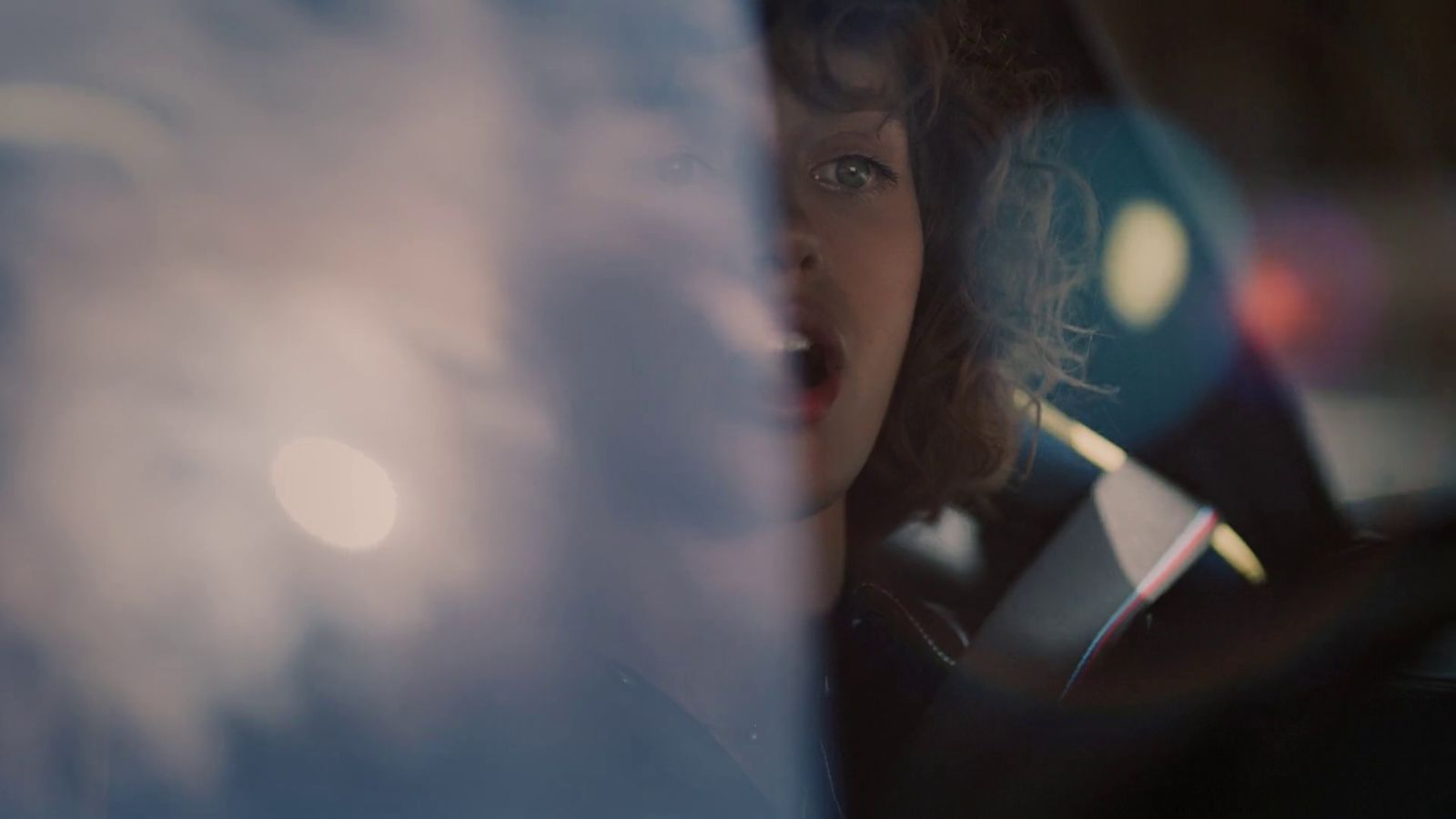 a woman driving a car with a surprised look on her face