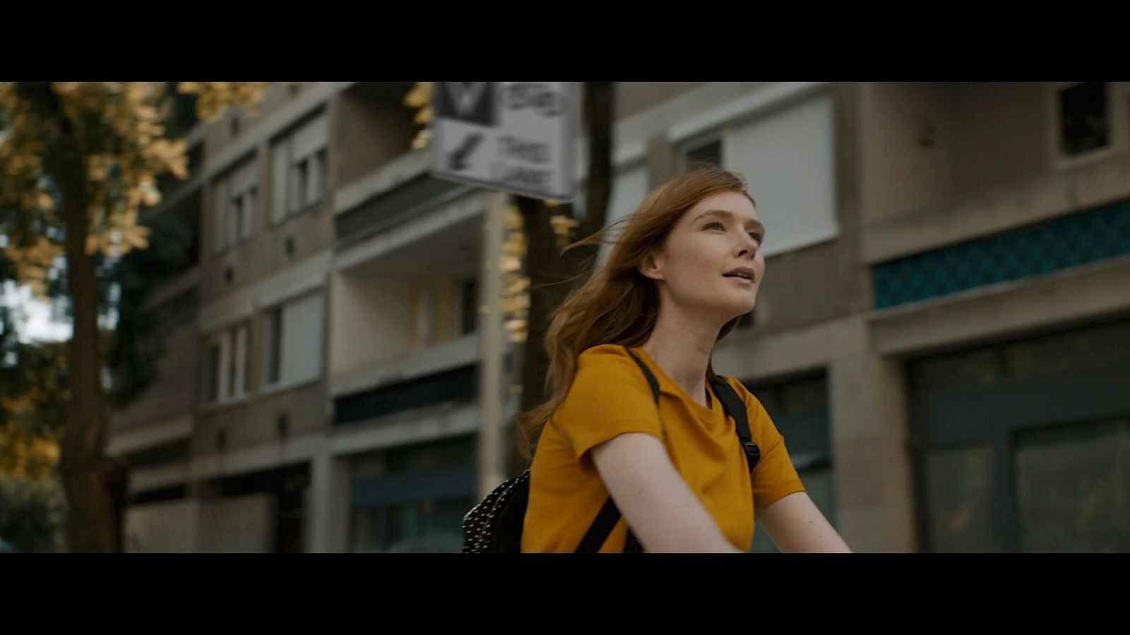 a woman walking down a street next to a tall building