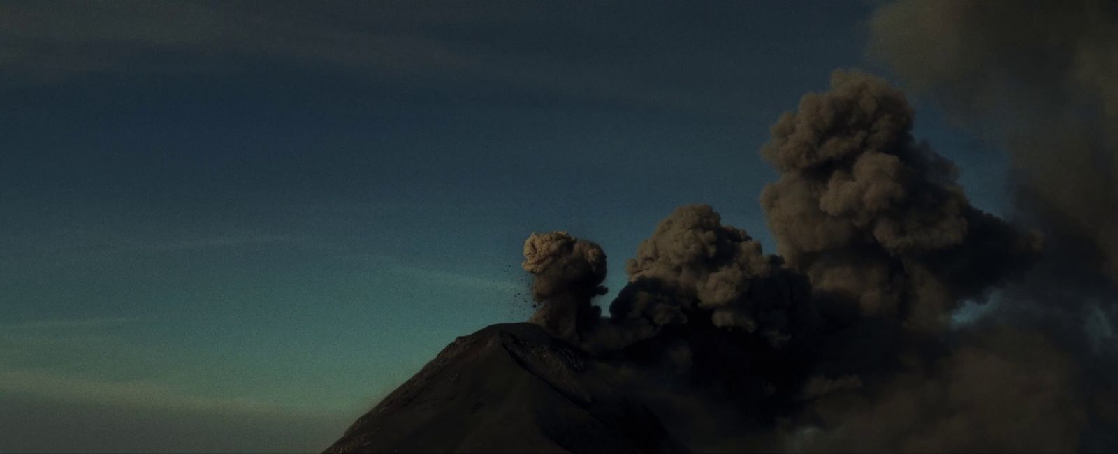 a large plume of smoke billows from the top of a mountain