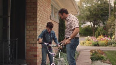 a man standing next to a boy on a bike