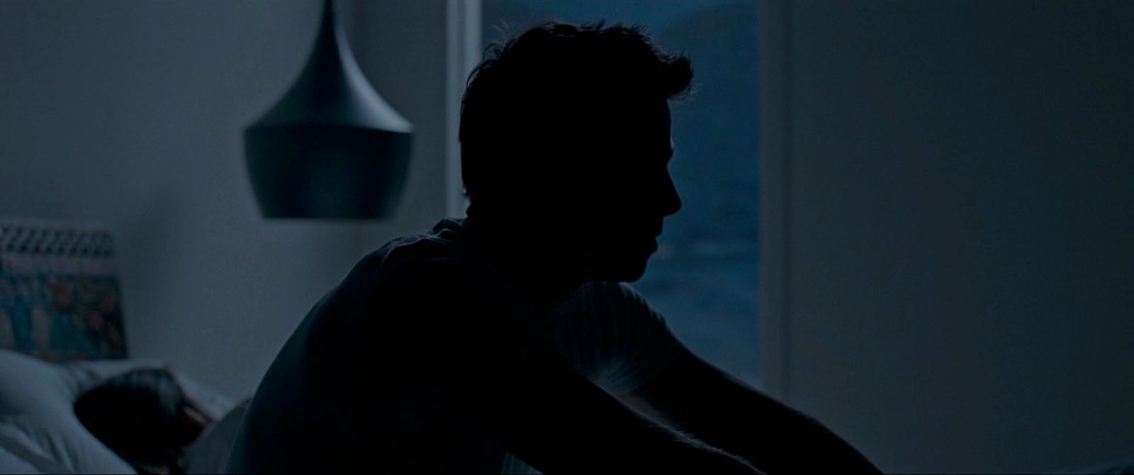 a man sitting in a bed in a dark room