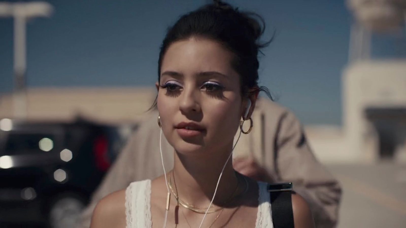 a woman wearing ear buds and a white tank top