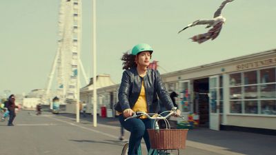 a woman riding a bike with a bird flying above her