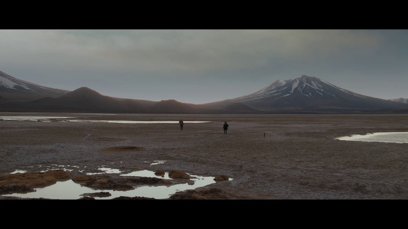 a couple of people standing on top of a dry grass field