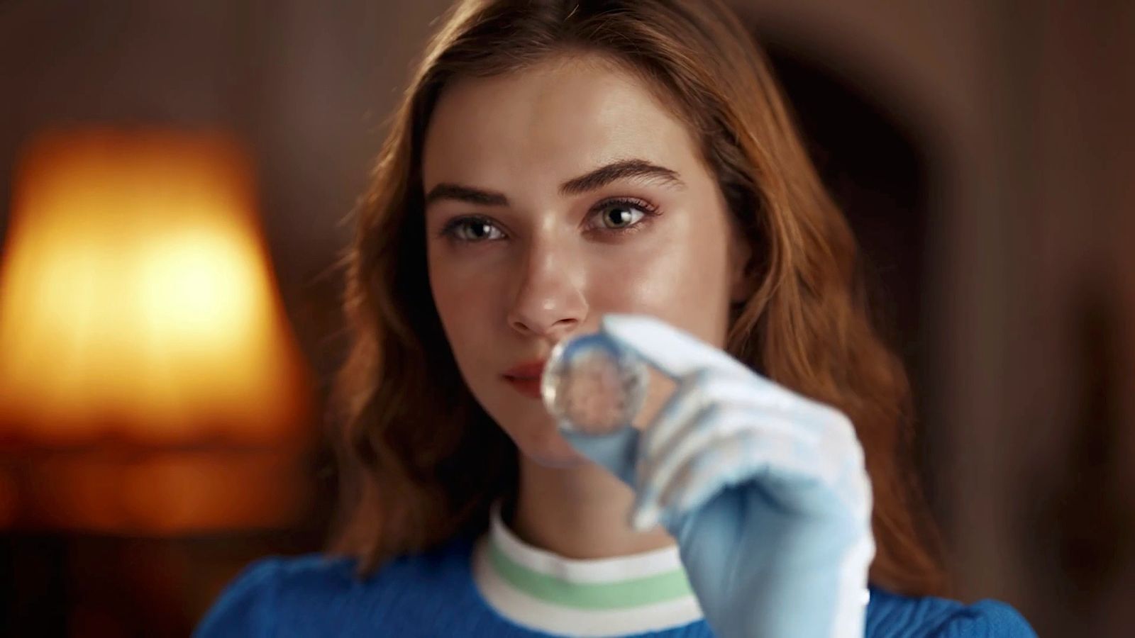 a woman in a blue sweater is holding a glass