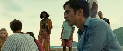 a group of people standing on a beach next to the ocean