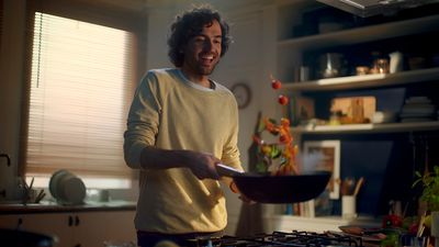 a man standing in a kitchen holding a frying pan