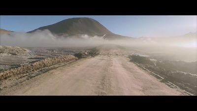 a dirt road with a mountain in the background