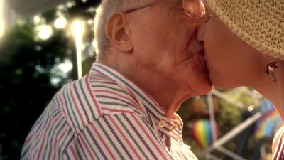 an older man and woman kissing each other