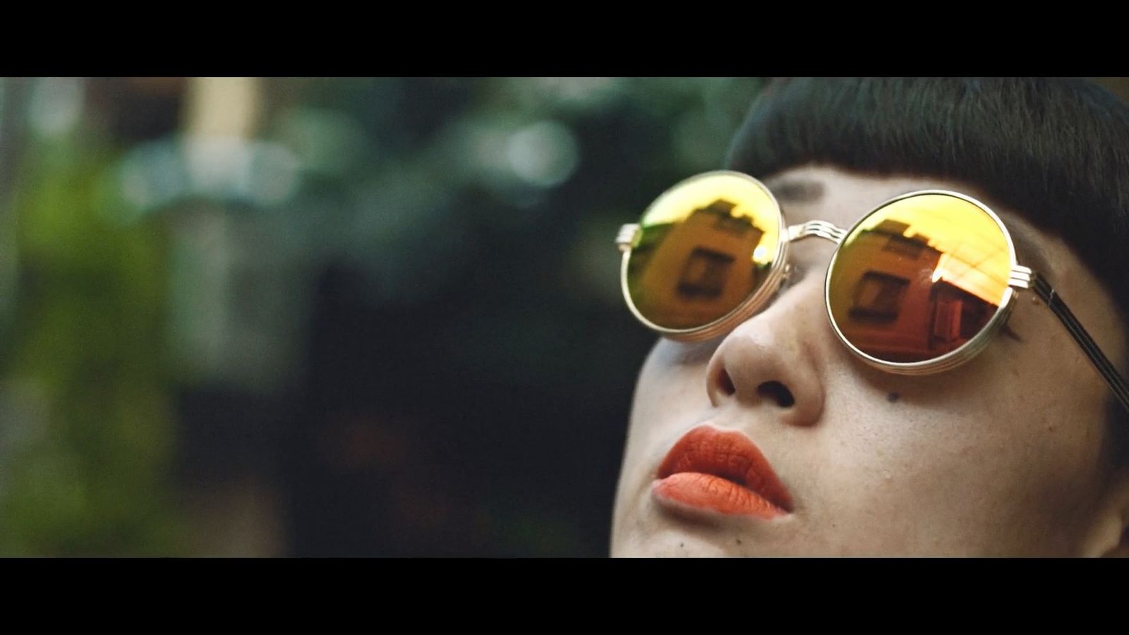 a woman wearing round sunglasses and orange lipstick