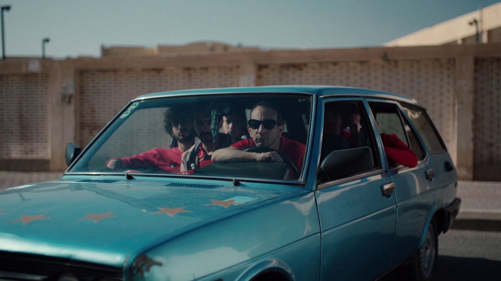 a group of men sitting in a blue car