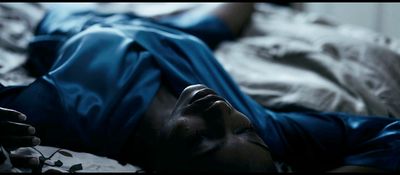 a man laying on a bed with a blue shirt on