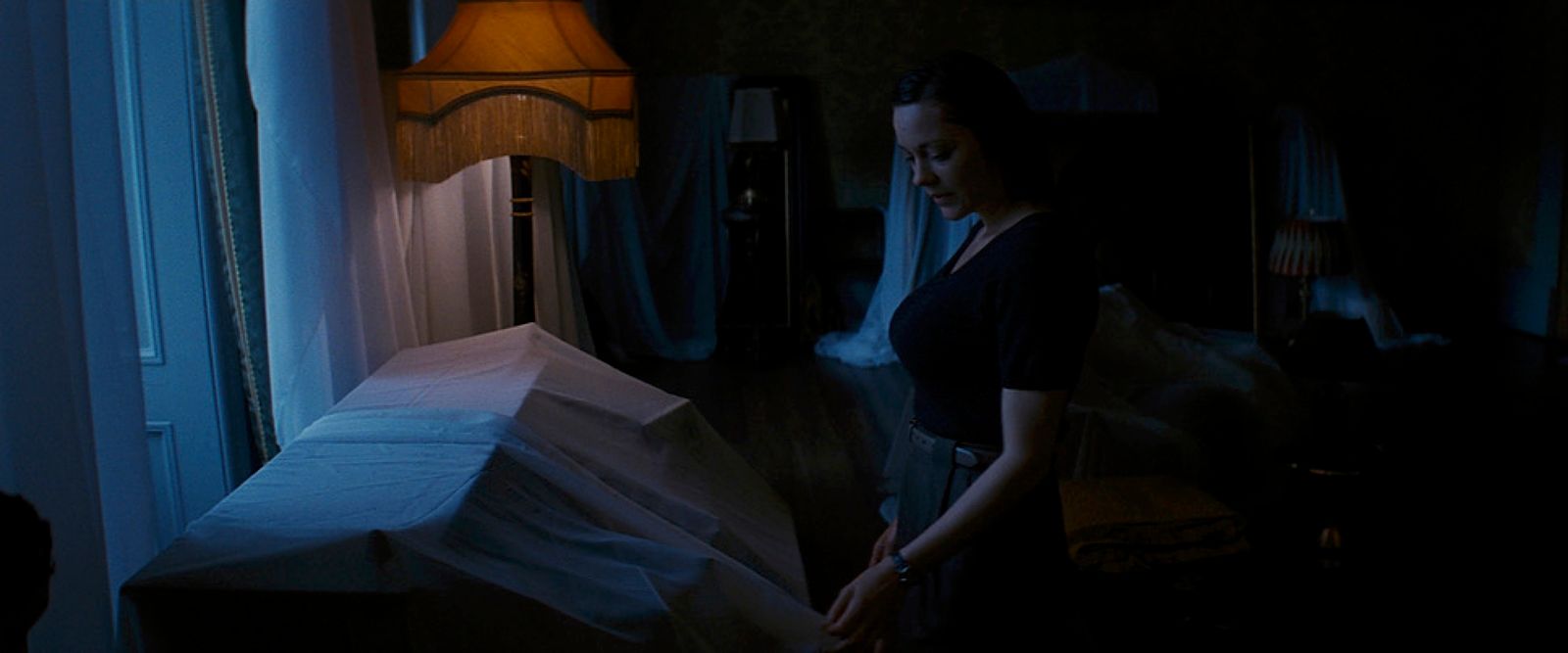 a woman standing next to a bed in a dark room