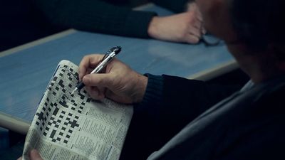 a man sitting at a table writing on a piece of paper