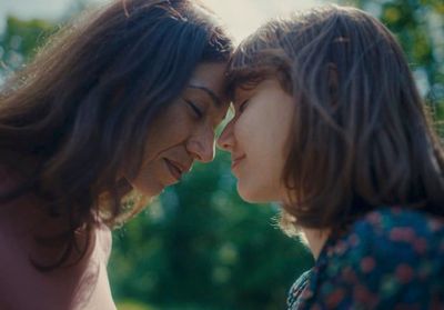 two women standing next to each other in front of trees