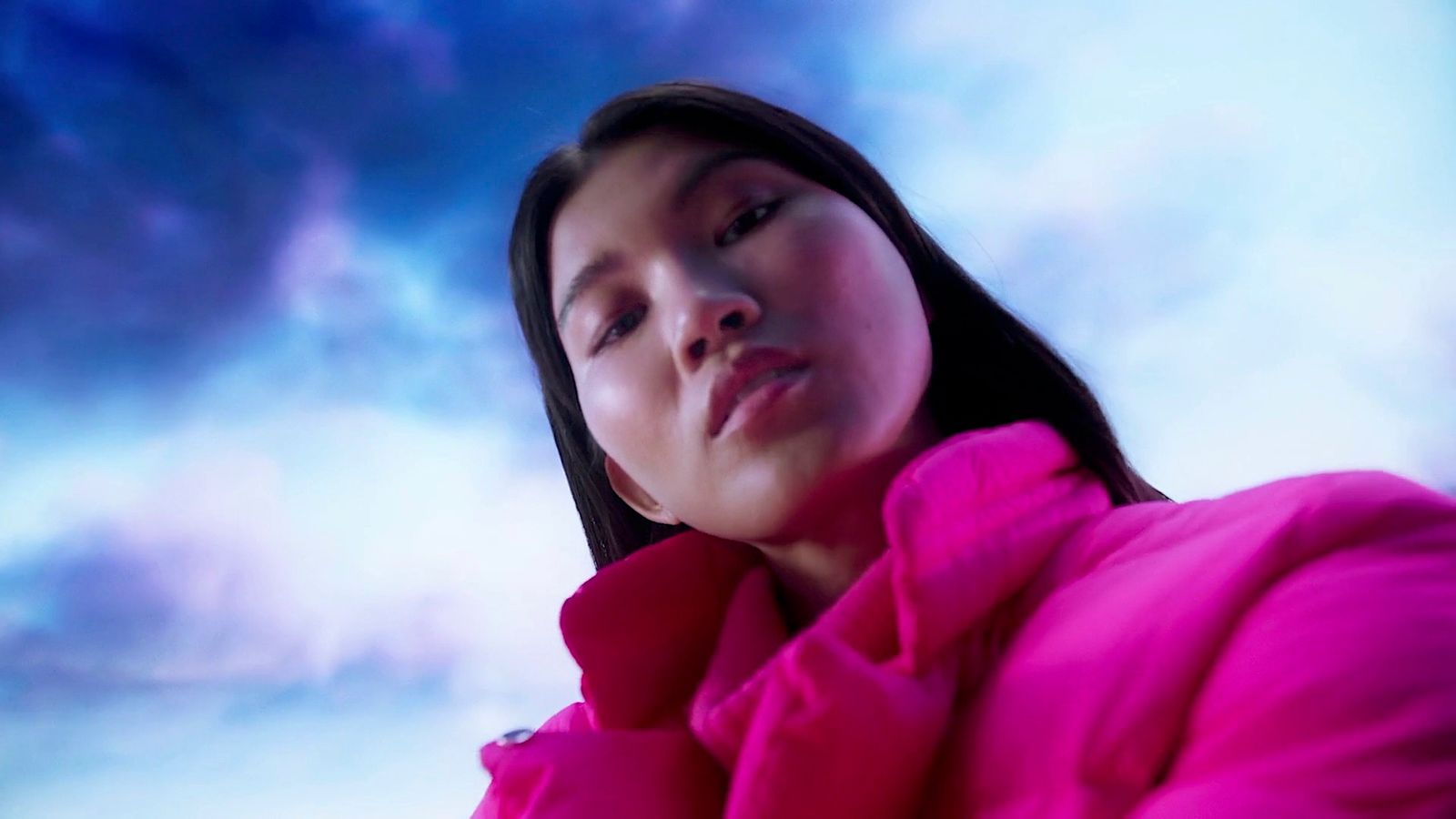 a woman in a pink coat looking up at the sky