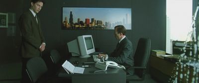 a couple of men standing around a desk with a computer