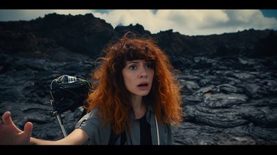 a woman with red hair standing in front of a mountain