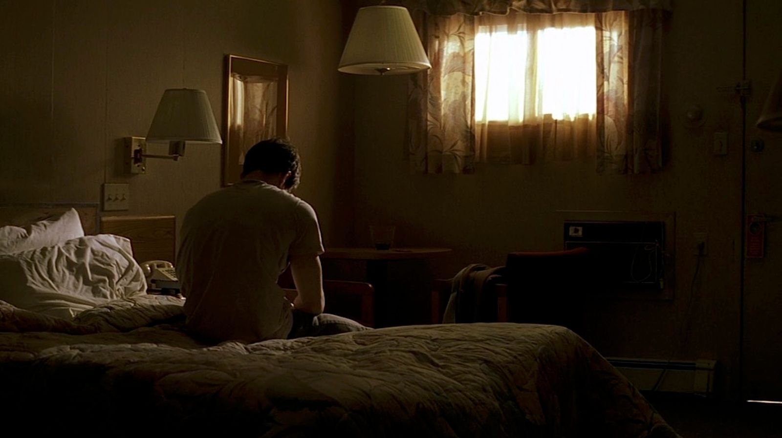 a man sitting on a bed in a dimly lit room