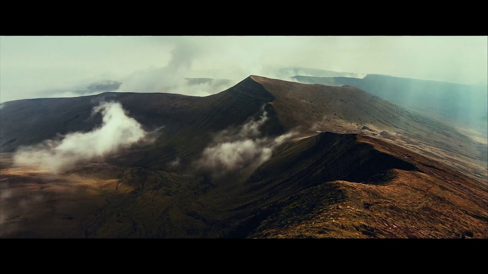 a view of a mountain with clouds coming out of it