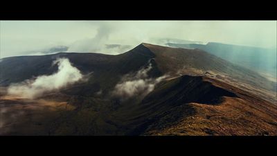 a view of a mountain with clouds coming out of it