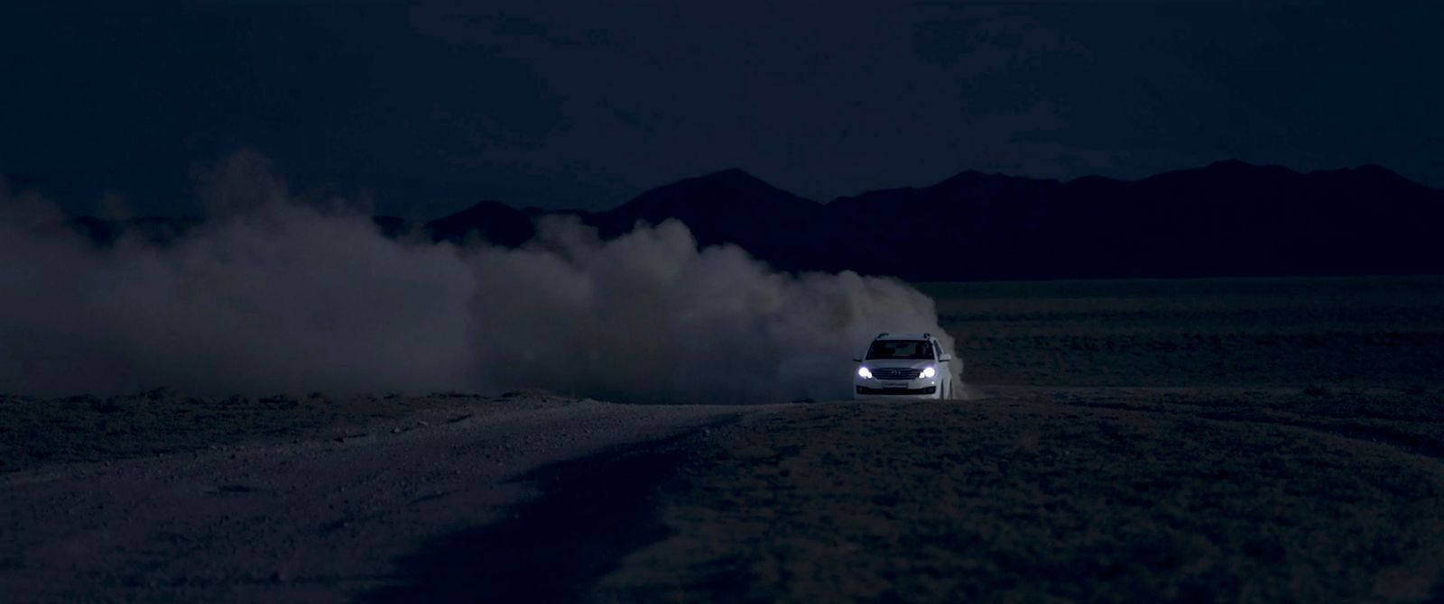 a car driving on a dirt road at night