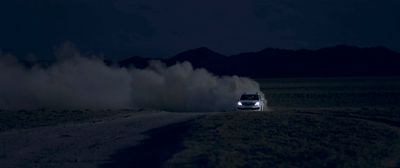 a car driving on a dirt road at night