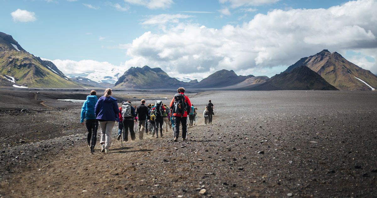 a group of people walking across a dirt field