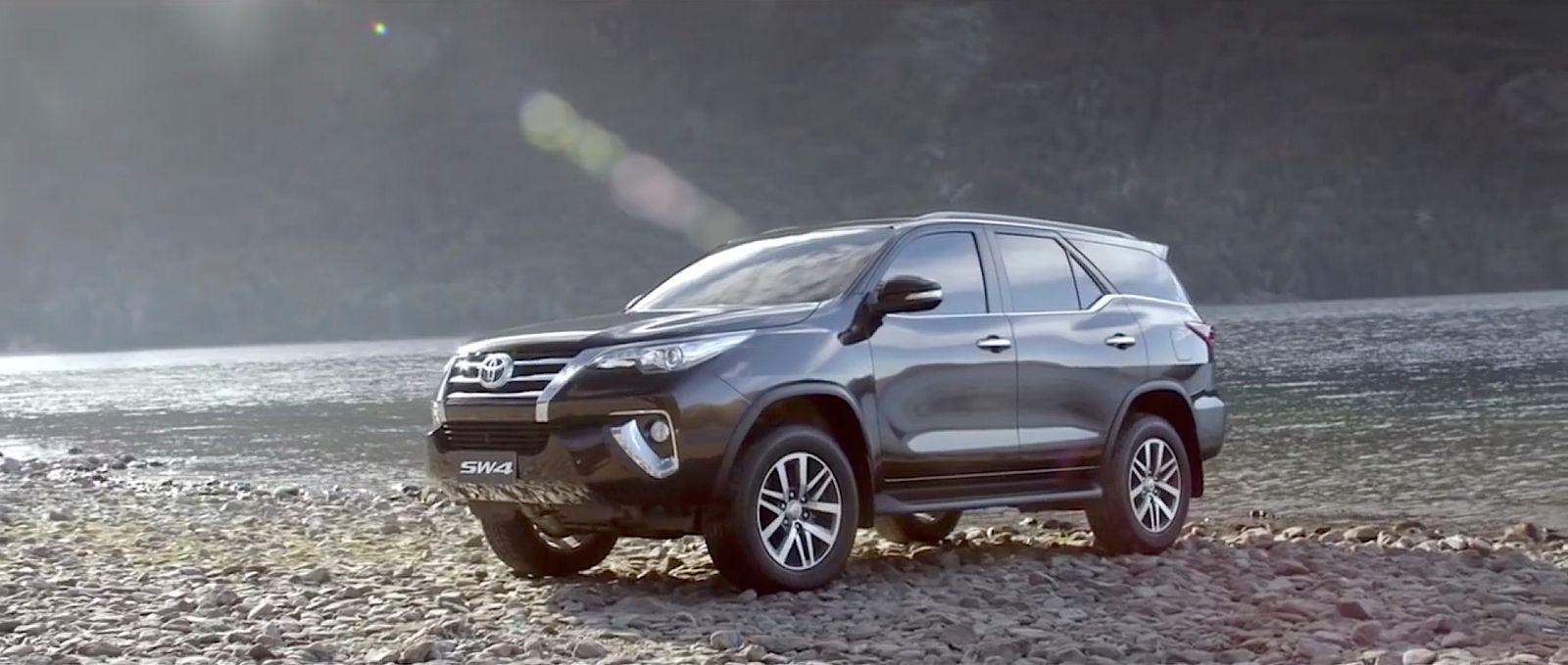 a grey suv parked on a rocky beach