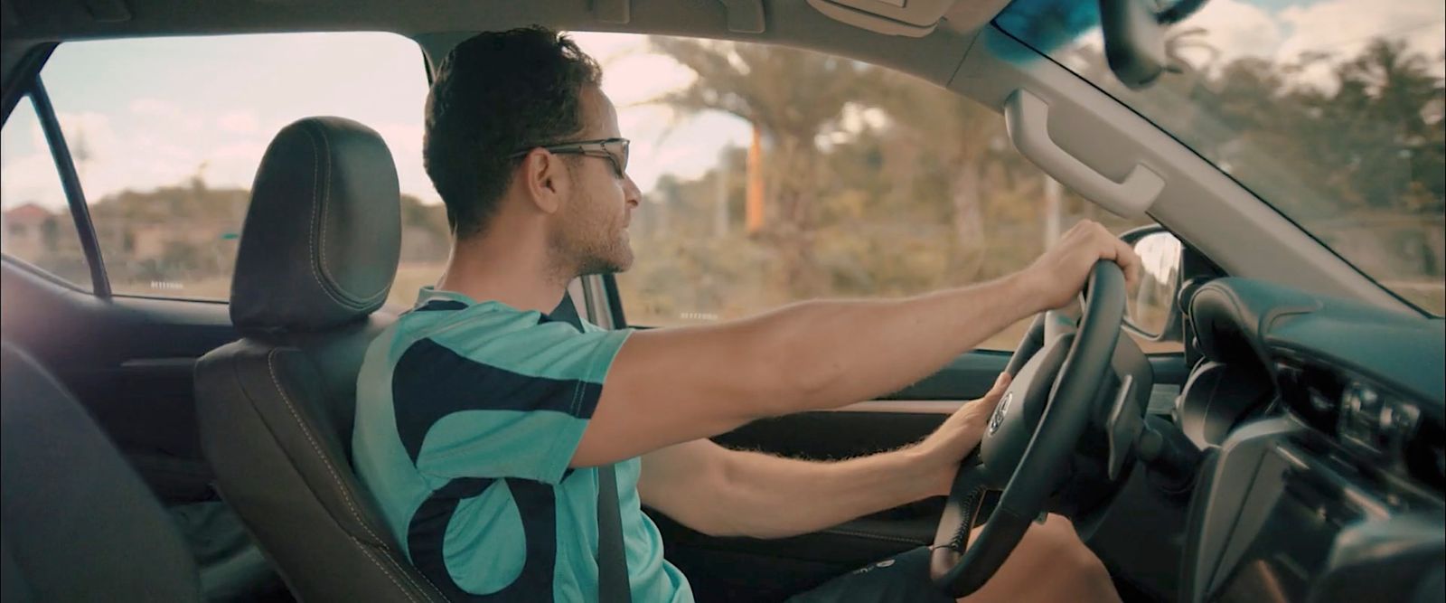 a man sitting in a car with his hand on the steering wheel