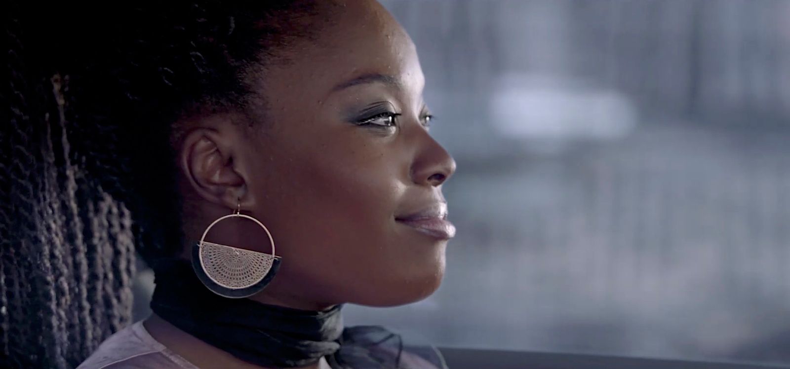 a woman sitting in a car wearing large earrings