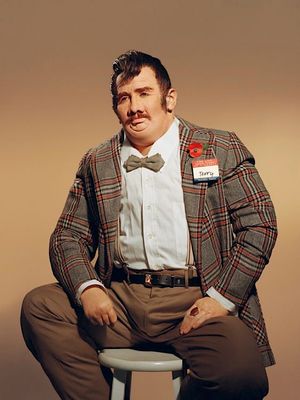 a man sitting on a stool wearing a suit and bow tie