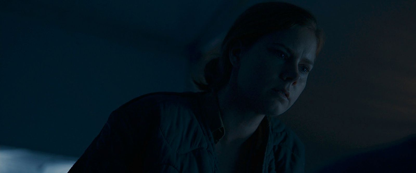 a woman standing in a dark room looking at something