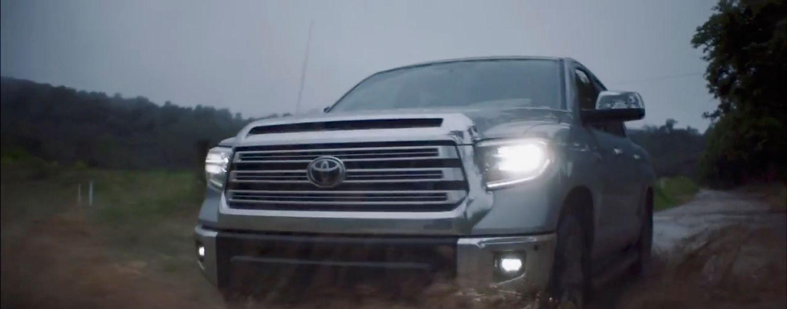 a silver truck driving down a dirt road