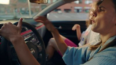 a woman driving a car with her hand on the steering wheel